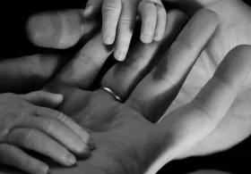 Black and white photo of 2 adult palm of hands holding baby hands. 