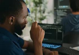 Man working in an office looking at two computer screens