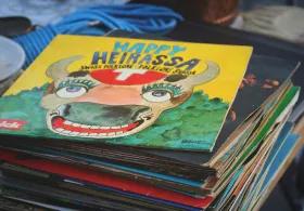 A stack of children’s books with colourful covers, set in front of shelves and background storage items
