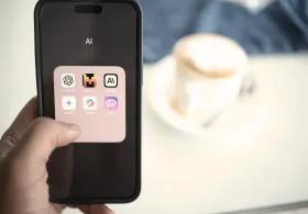 A person holding a mobile phone displaying AI-related apps including ChatGPT, with a blurred background showing a coffee on a table