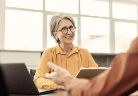 Lady holding notes smiling at person opposite her