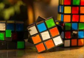 A table with 4 worn and unevenly turned Rubik’s Cubes, showing faded and peeling stickers, with mismatched colours and tilted angles