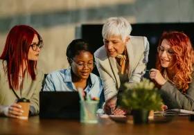 Students and tutor working together around a laptop