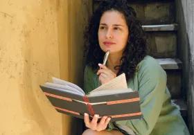 Lady holding a book with a pen in hand, thinking