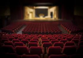 Looking down at a stage in an empty theatre of red seats