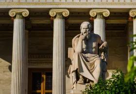 Statue of a philosopher outside a building with columns