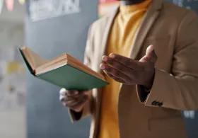 Person reading from a book and gesturing