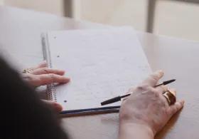 Close up of a woman's hands, poised ready to continue writing on paper