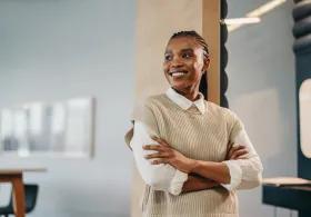 Woman standing with arms crossed smiling in office environment