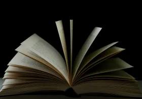 An open book with its pages fanned out against a black background