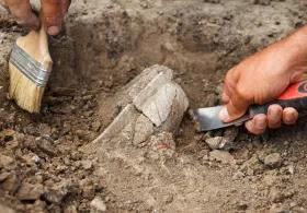 Archaeological excavations, archaeologists work, dig up an ancient clay artifact with special tools in soil.
