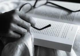 black and white image of book and glasses resting ontop