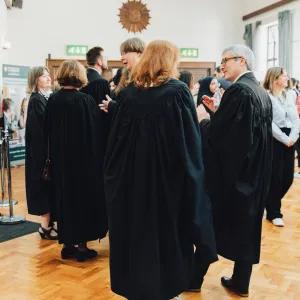A large reception room full of Cambridge academics in black gowns and other people chatting and mingling. 