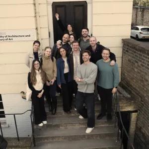 A group of apprentices standing on the steps outside a University of Cambridge faculty building.