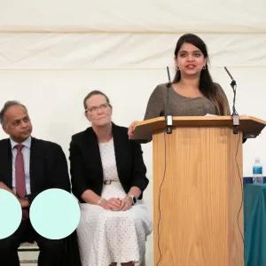 woman stood at podium delivery a speech