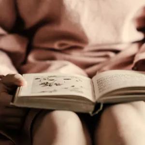 A child sitting on a bed reading a book. 