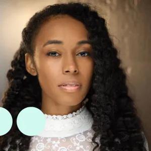 Headshot of woman with thick black curly hair, looking directly into camera