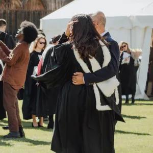 A graduate and guest posing for a photo on graduation day