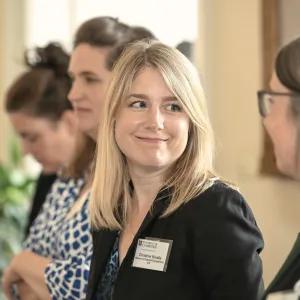 A group of four women wearing name badges. Two of them are smiling at each other. 