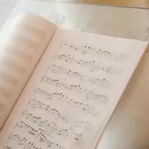 An open book of sheet music on a stand, showing pages filled with musical notes