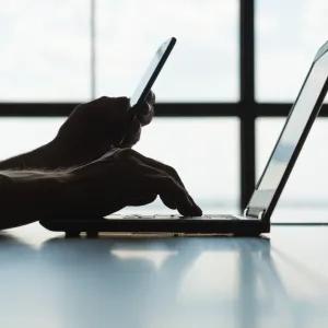 Student logging into a laptop with phone