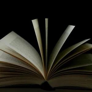 An open book with its pages fanned out against a black background