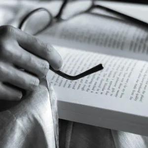 black and white image of book and glasses resting ontop