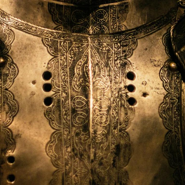 A close-up of a suit of armour in a darkly lit room. 