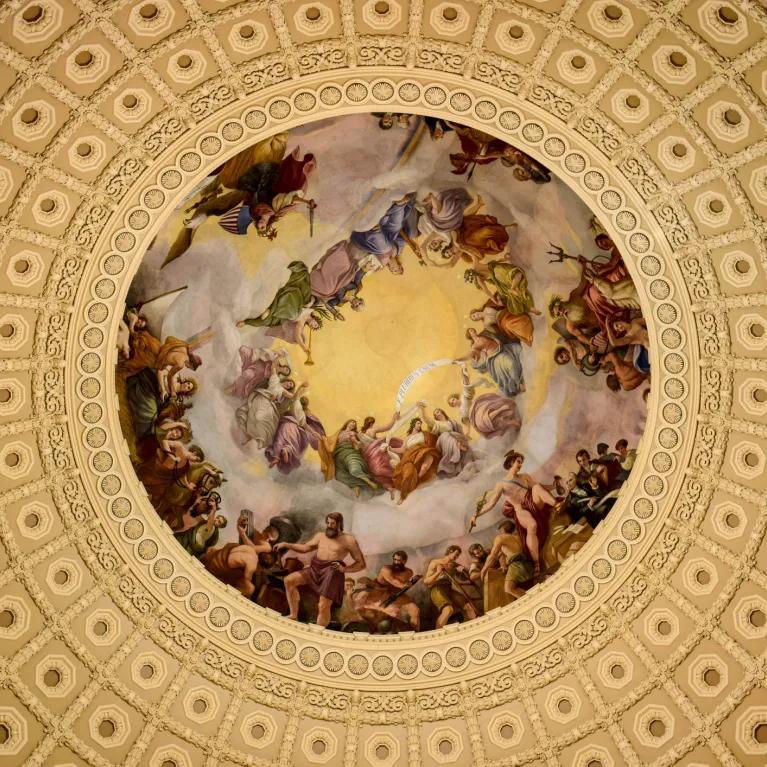 Figurative painting in a circular frame of a domed ceiling, viewed from below. 