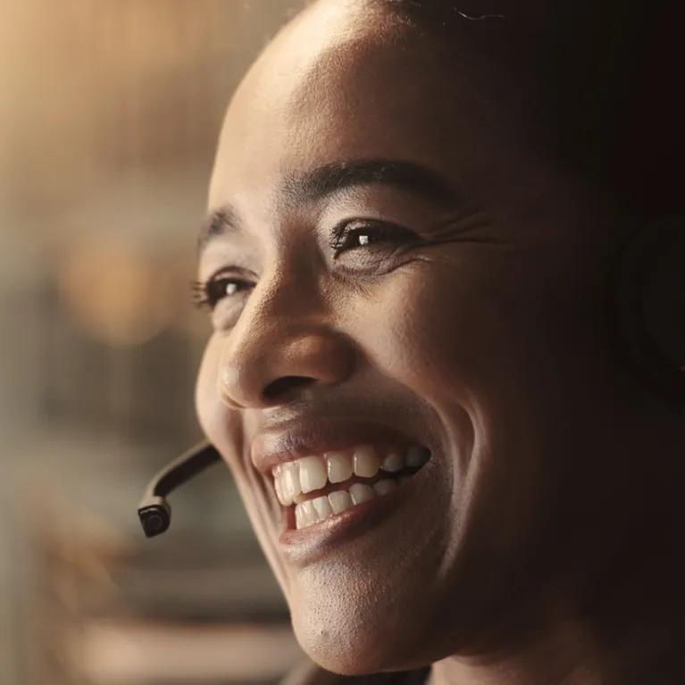 A smiling woman wearing a headset.
