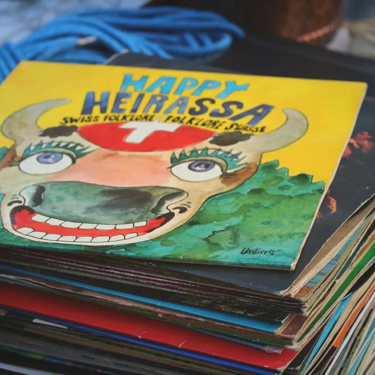 A stack of children’s books with colourful covers, set in front of shelves and background storage items