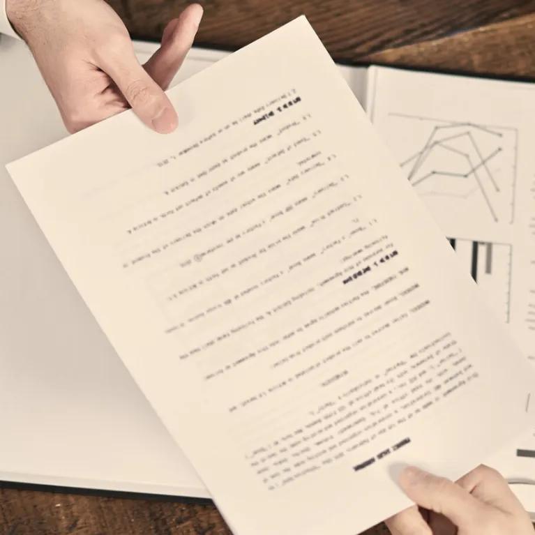 One person passing a document to another person