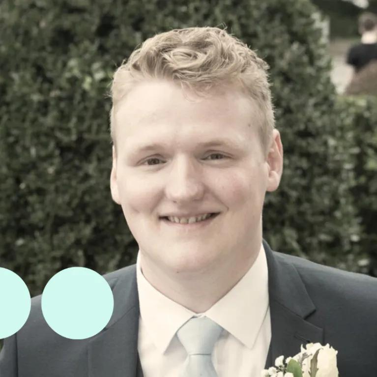 man with light blonde hair, in suit smiling for photo 