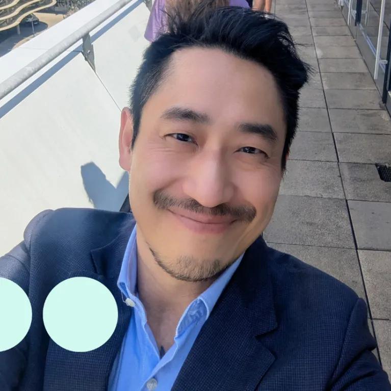 Selfie taken by Asian man, smiling and wearing a suit 