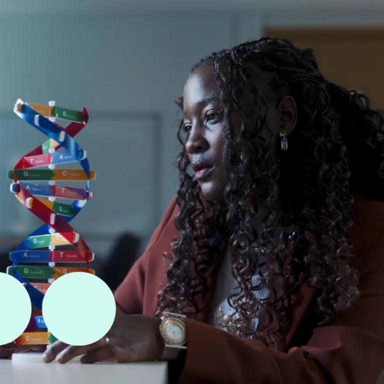 Black woman, sat analysing a DNA model 