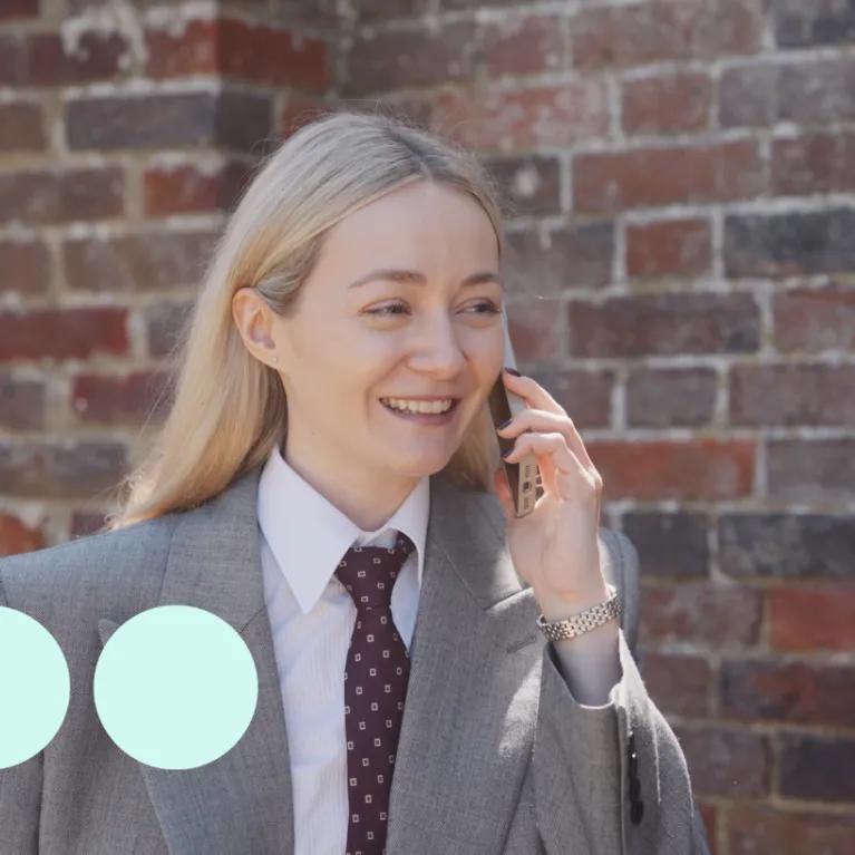 Blonde woman wearing suit, walking and talking on a mobile phone
