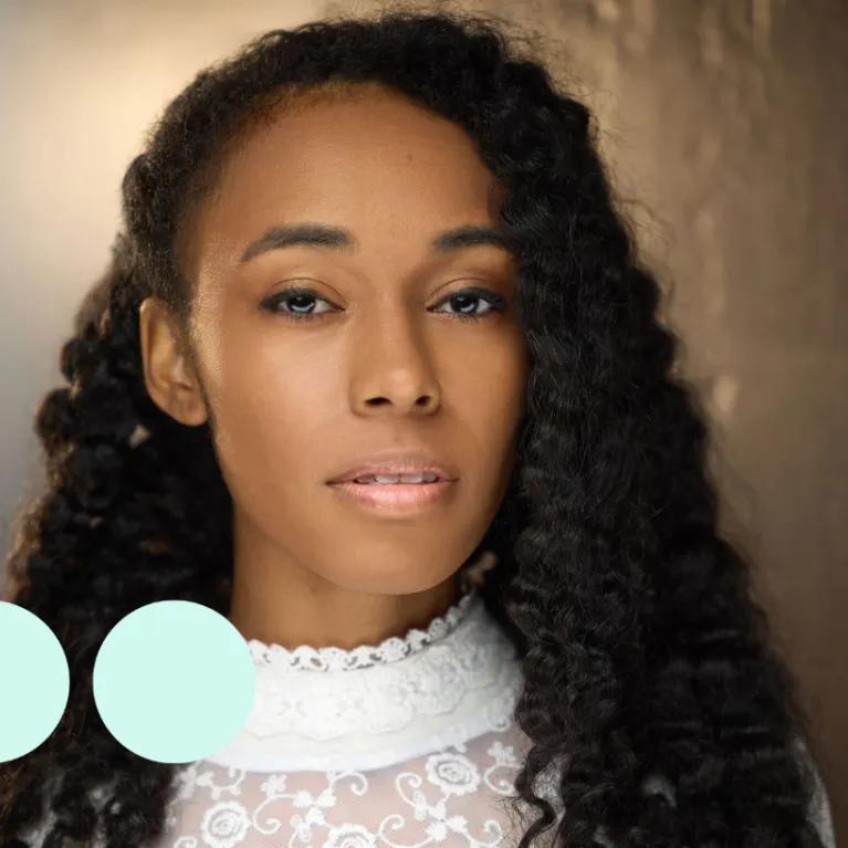 Headshot of woman with thick black curly hair, looking directly into camera