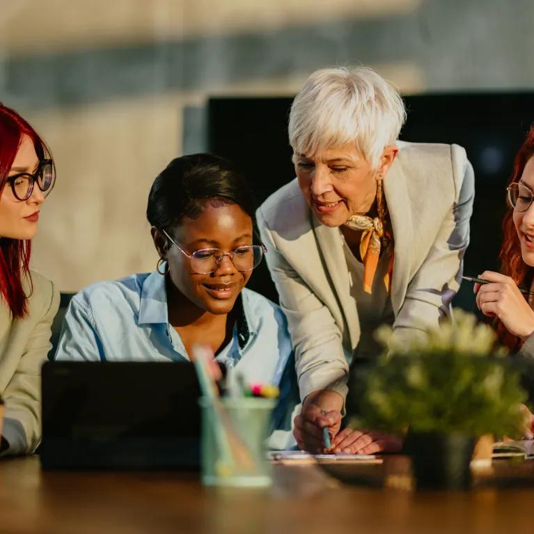 Students and tutor working together around a laptop