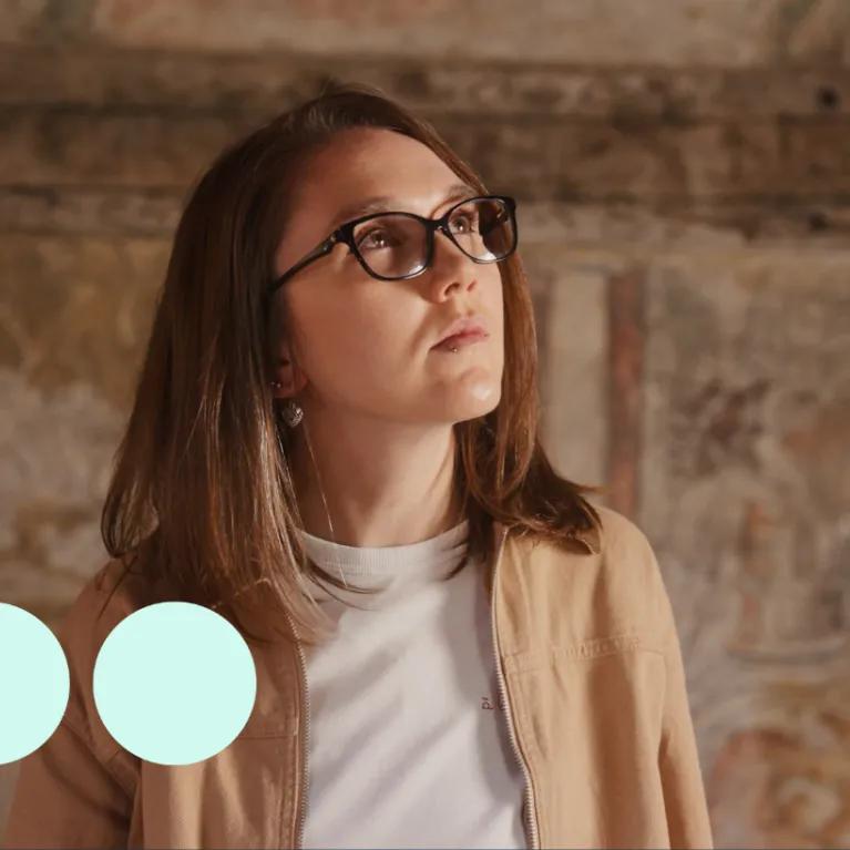 Woman with glasses looking up at tapestry 