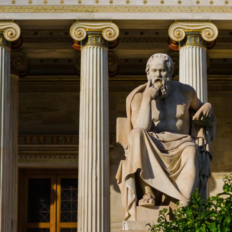 Statue of a philosopher outside a building with columns