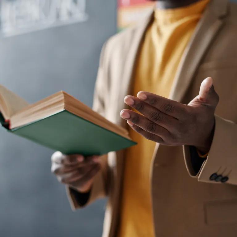 Person reading from a book and gesturing