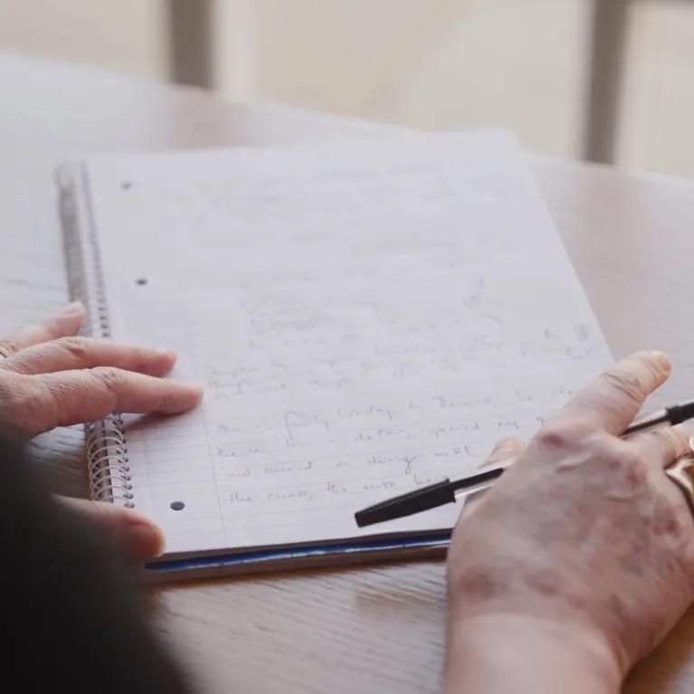 Close up of a woman's hands, poised ready to continue writing on paper