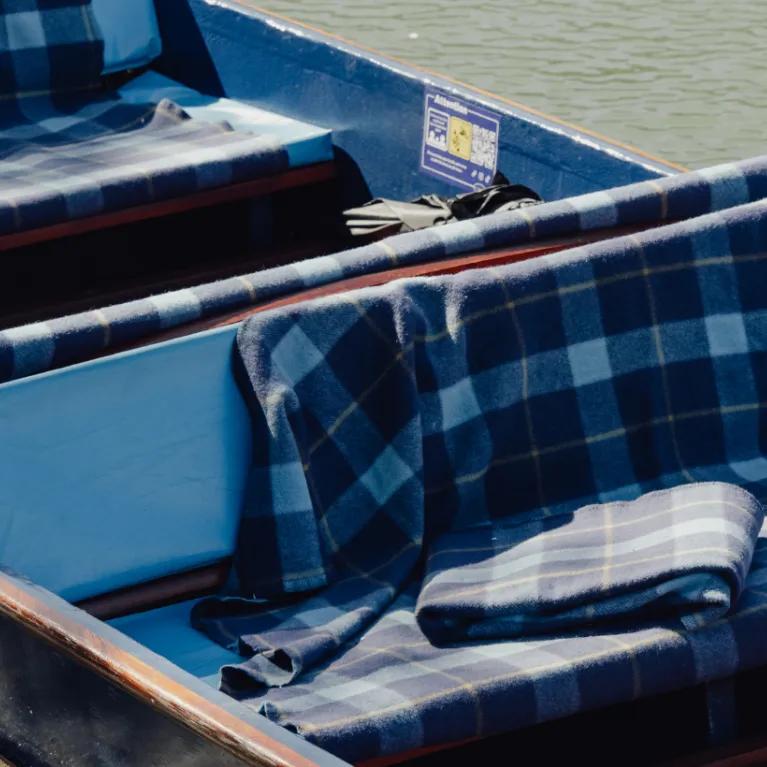 A punt with tartan blankets on the river cam.