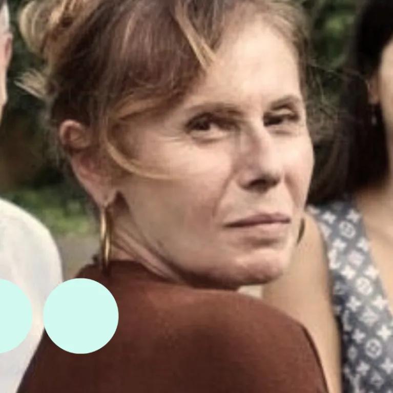 Woman with light brown hair tied up, looking over her shoulder for photo