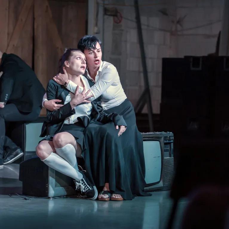 Two actors on a stage embracing