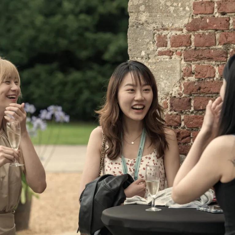 3 girls laughing in conversation at a garden party 