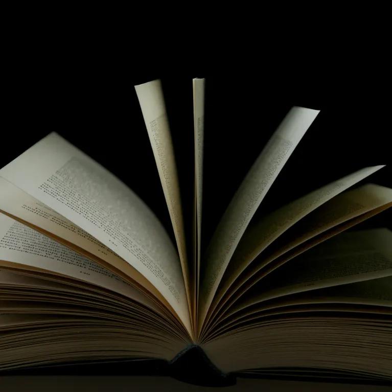 An open book with its pages fanned out against a black background