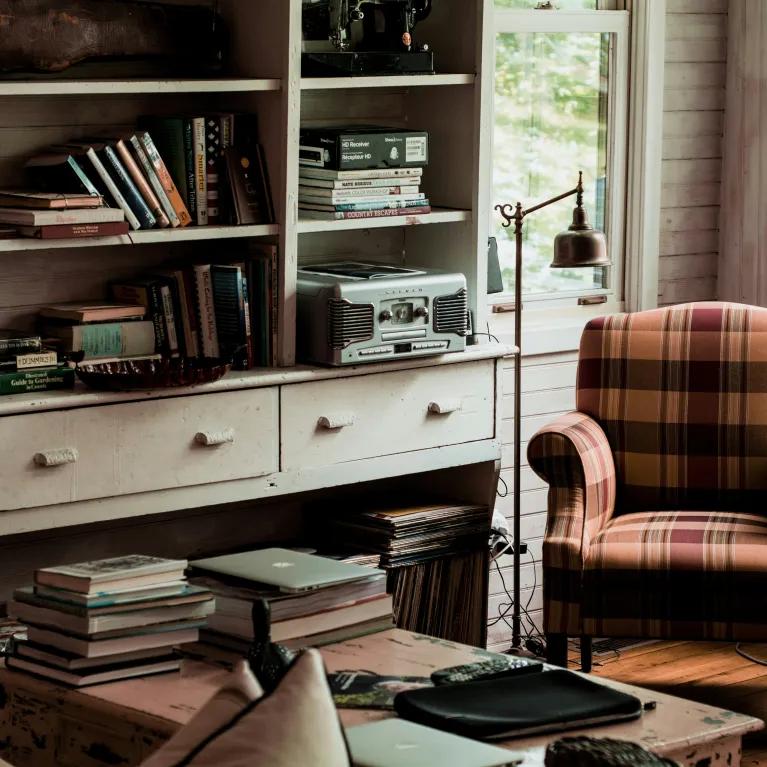 A living room with a vintage arm chair and desk with a bookcase. 