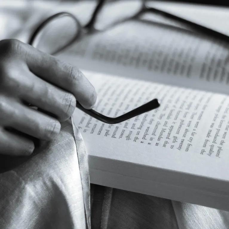black and white image of book and glasses resting ontop