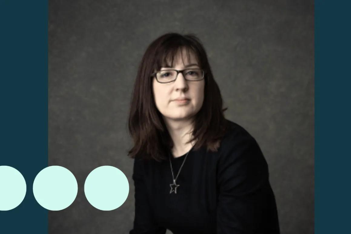 Headshot of woman with dark hair and glasses